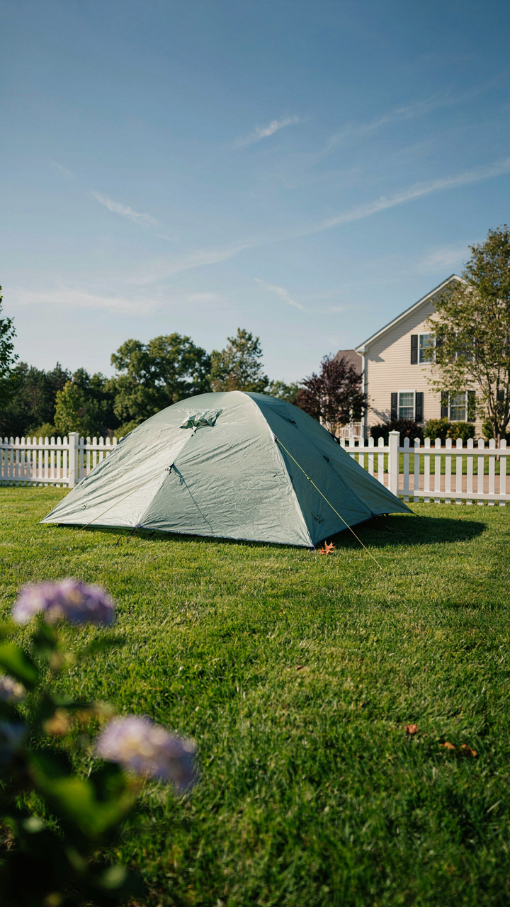 A small backpacking tent sits on a manicured lawn.