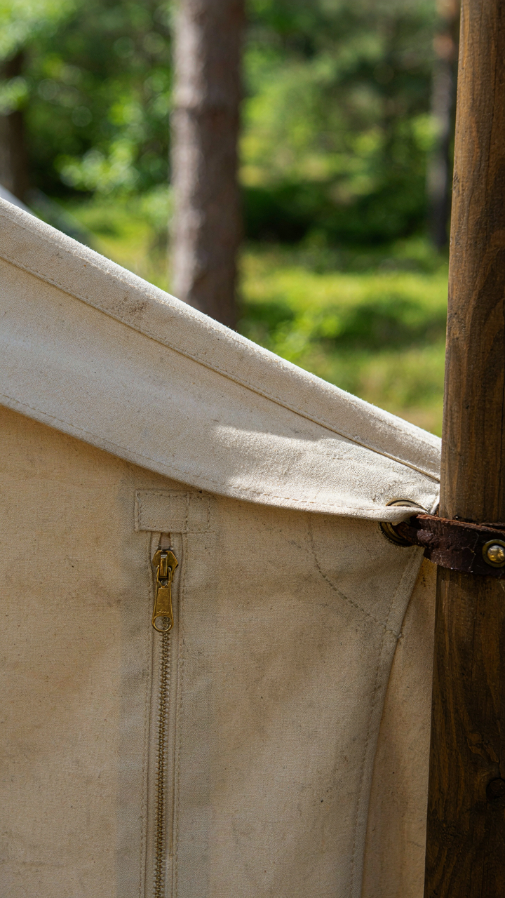 A close up of a premium canvas glamping tent, showing its sturdy wooden frame.