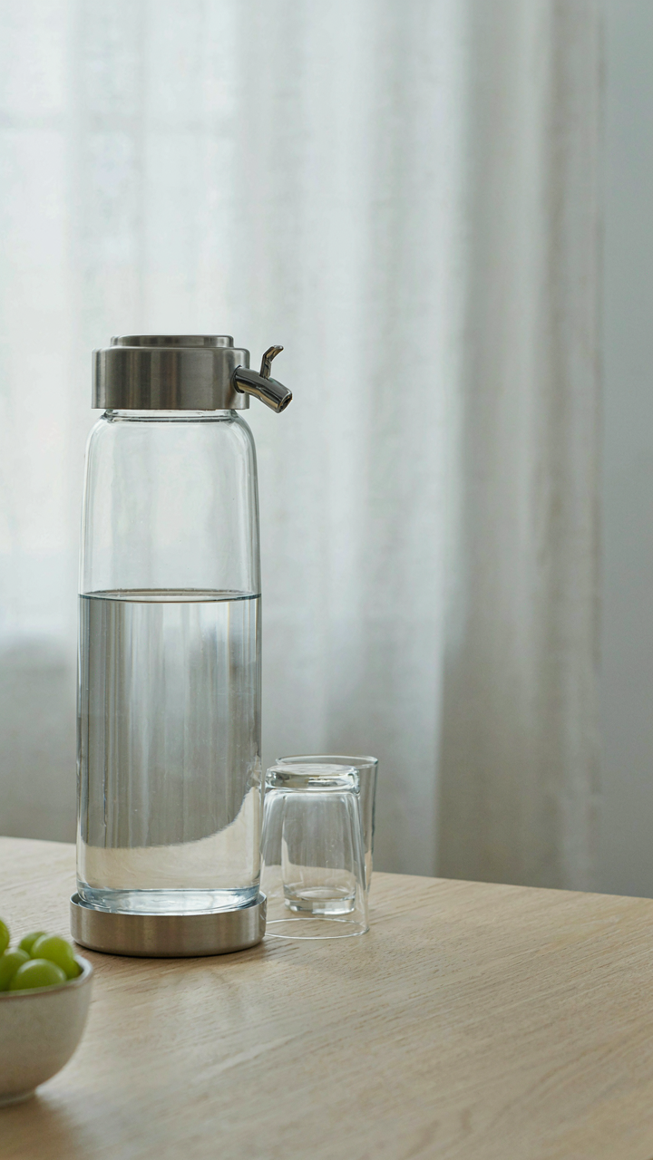 A simple glass water dispenser is clearly displayed on a table.