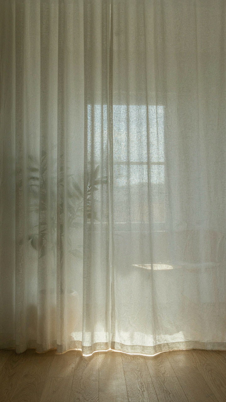 Bright light diffuses through a sheer white curtain, making shapes blurry.