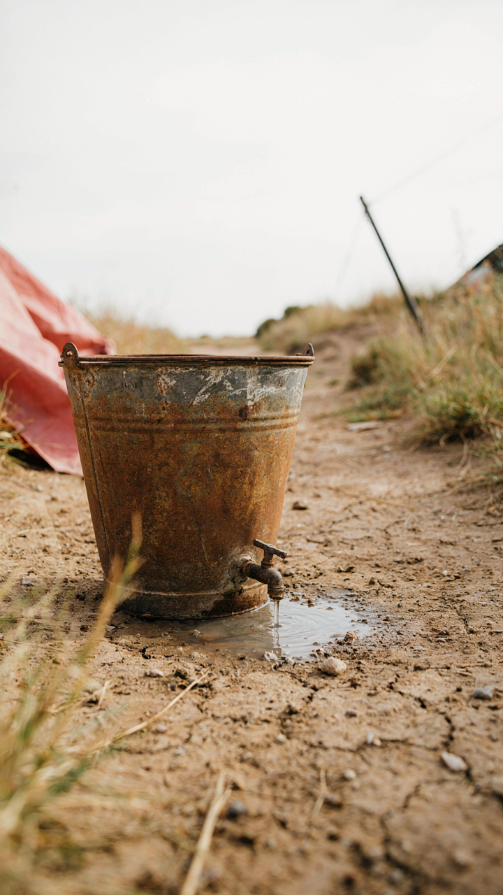 A rusted, leaking bucket serves as a poor diy camp shower.