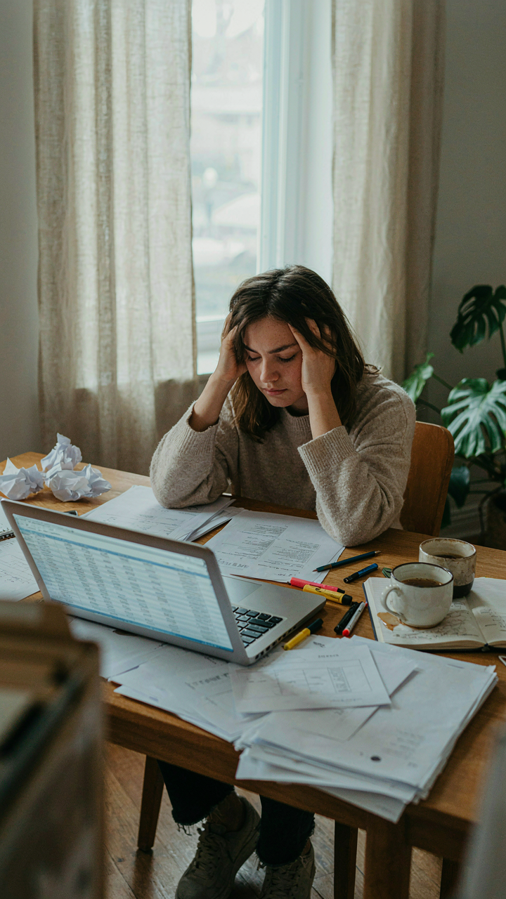 A cluttered desk shows many papers, pens, and coffee cups.