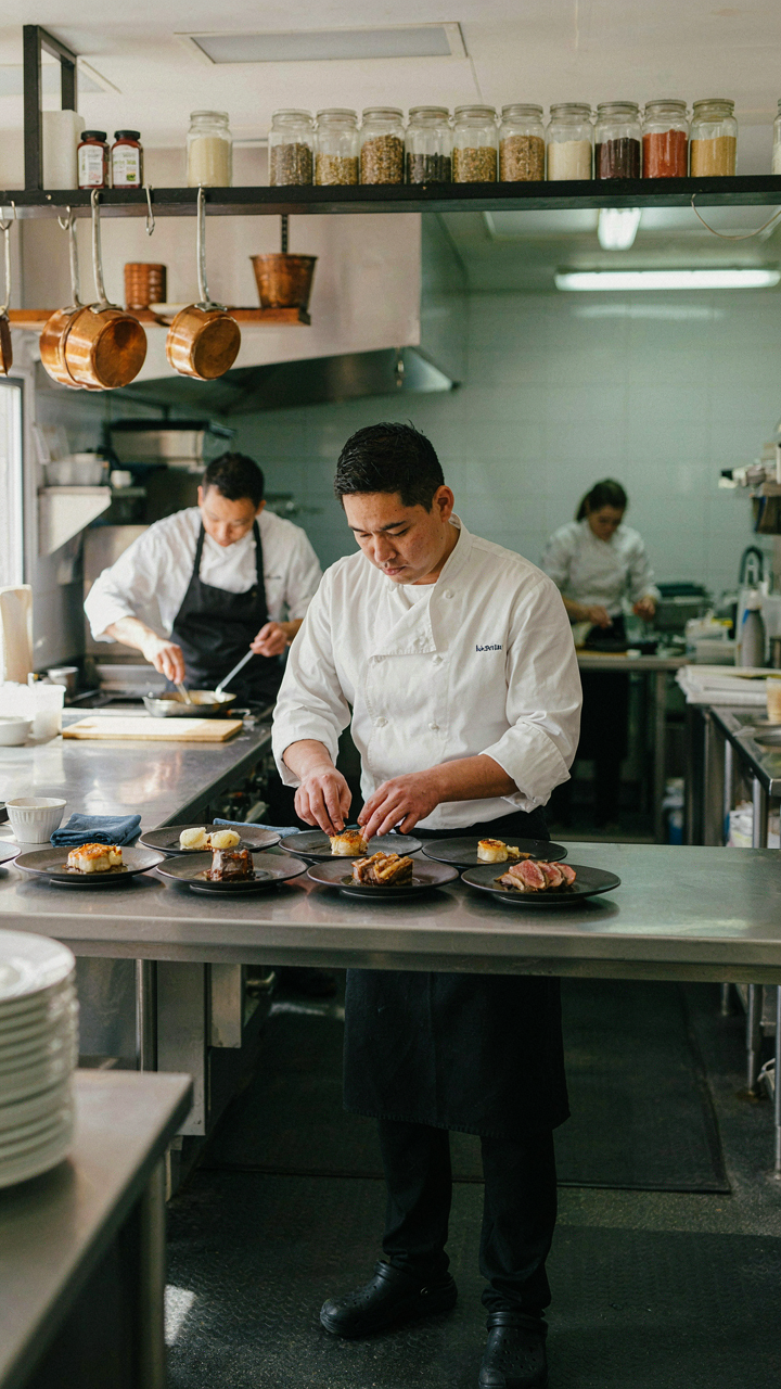 A chef swiftly garnishes a few dishes on a kitchen pass.