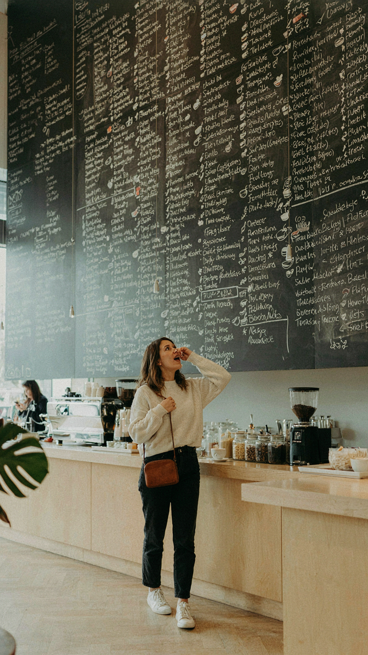 A person looks confused at a long menu board with many drink choices.
