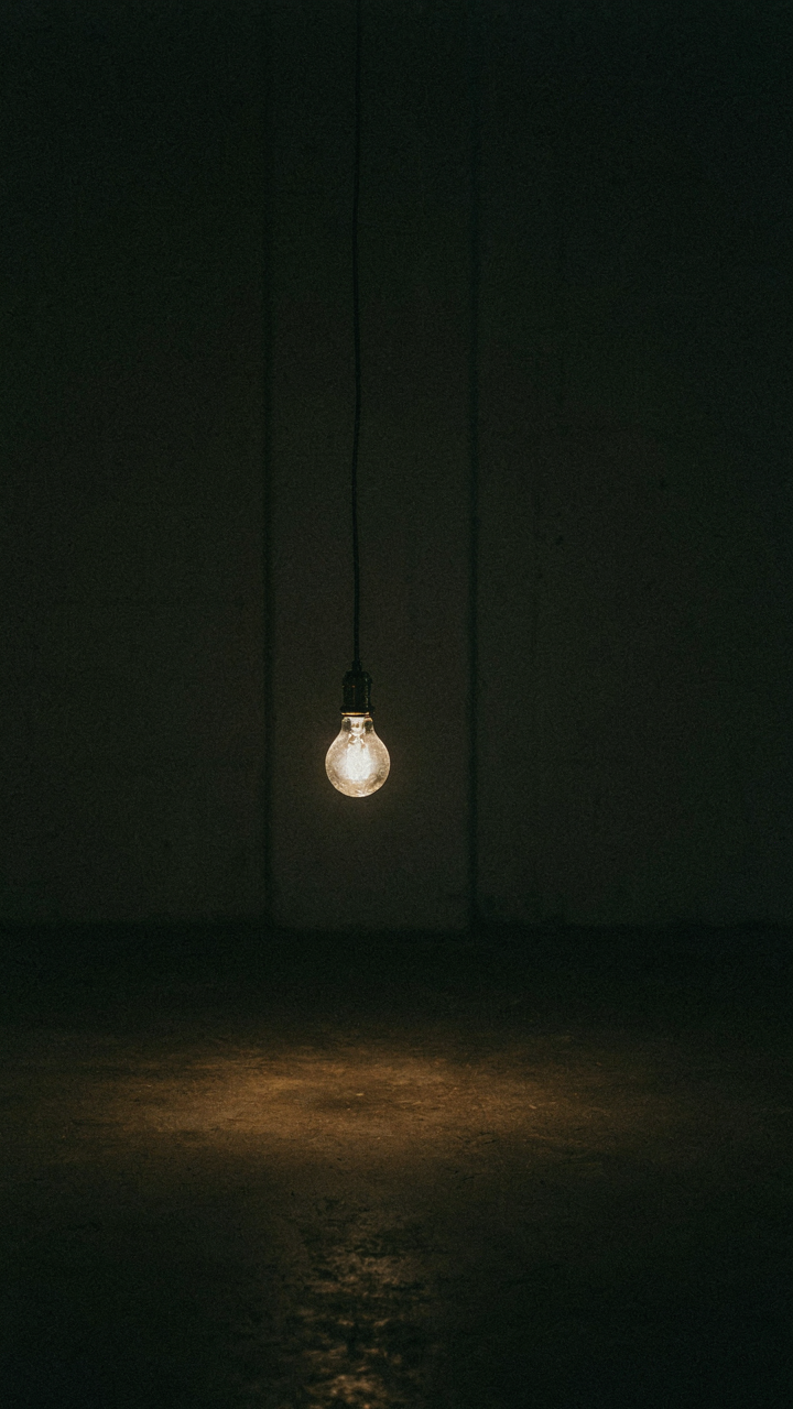 A single bright light bulb illuminates a small circle below it.