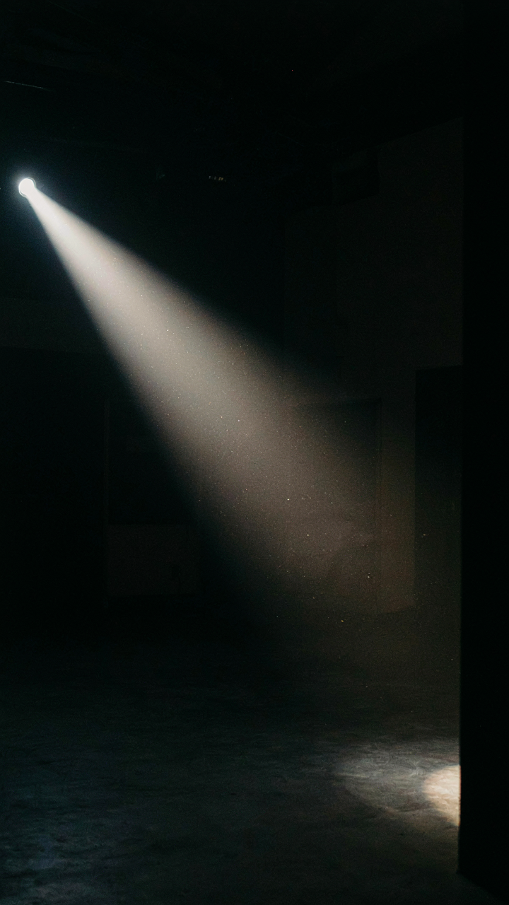 A single spotlight beam spreads out and dims across a dark room.