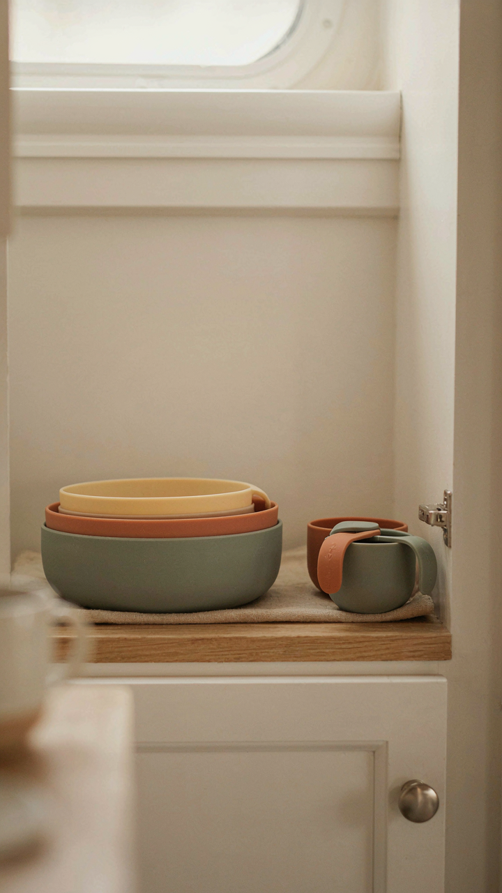 Collapsible silicone bowls and measuring cups stored in an RV kitchen cabinet.