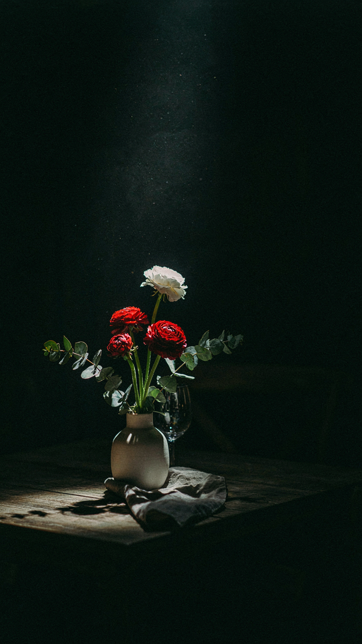 A single spotlight illuminates a small centerpiece on a dark outdoor table.