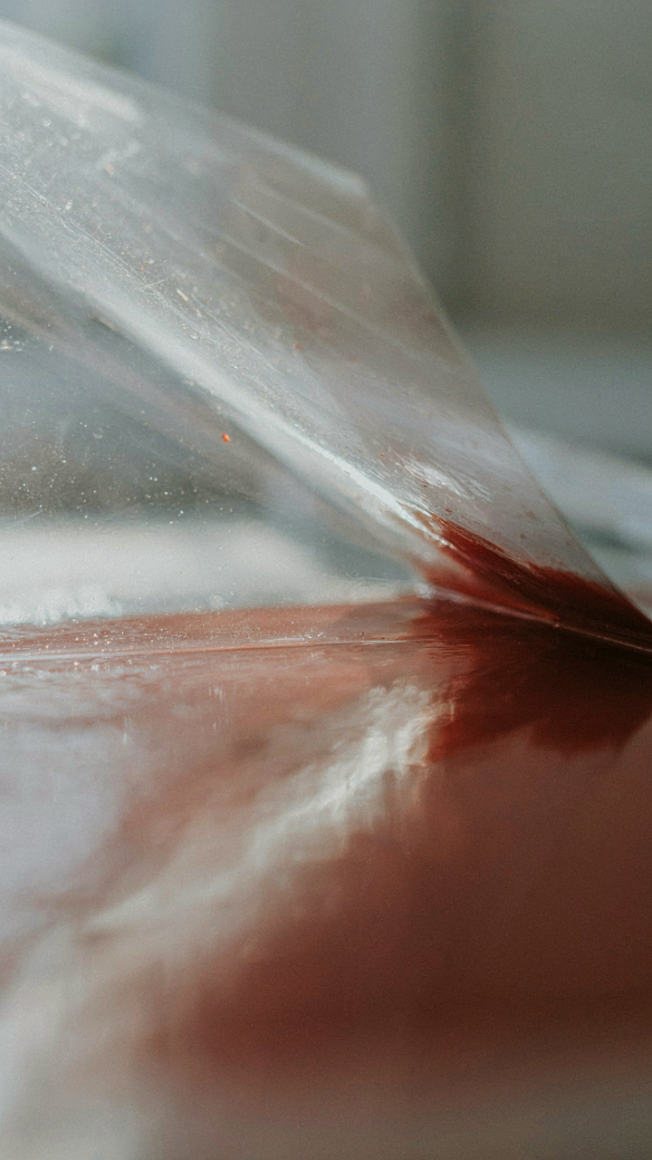 A transparent protective film is peeled from a glossy painted surface.