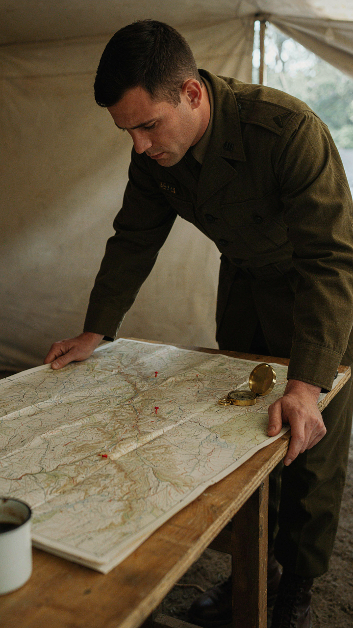 A military officer in uniform looking at a map with few markers.