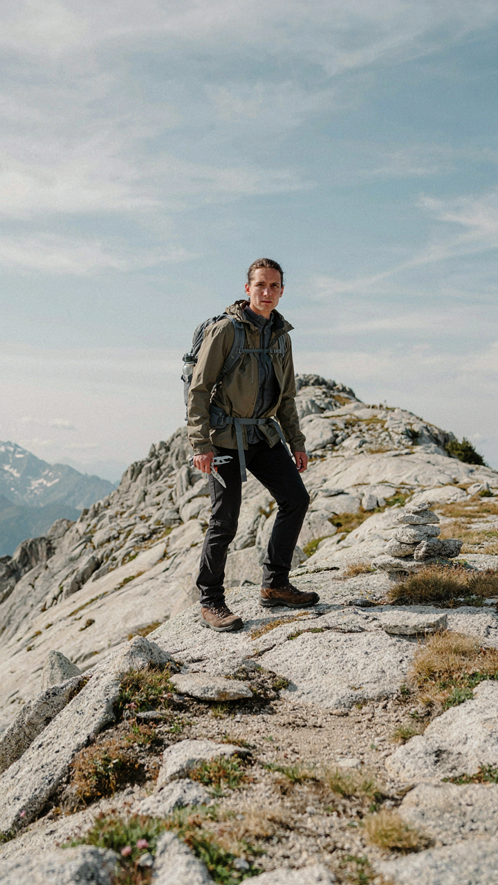 A hiker carries a lightweight tool in a mountain landscape.