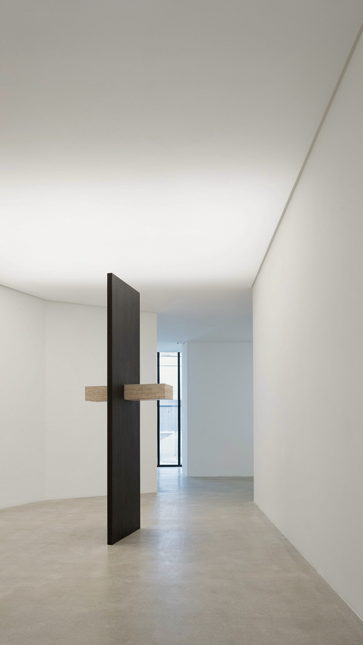 A modern art gallery shows a single, striking minimalist sculpture in a white room.