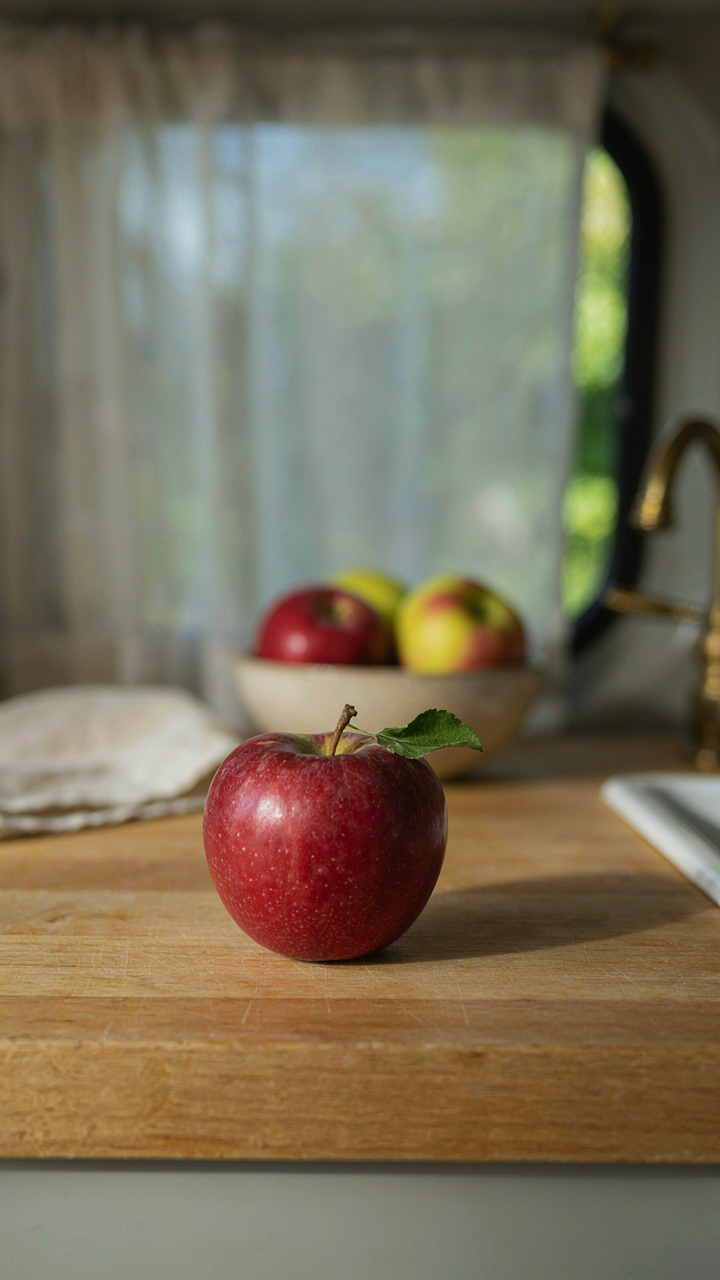 One bright red apple sits alone on a very small counter in a van kitchen.
