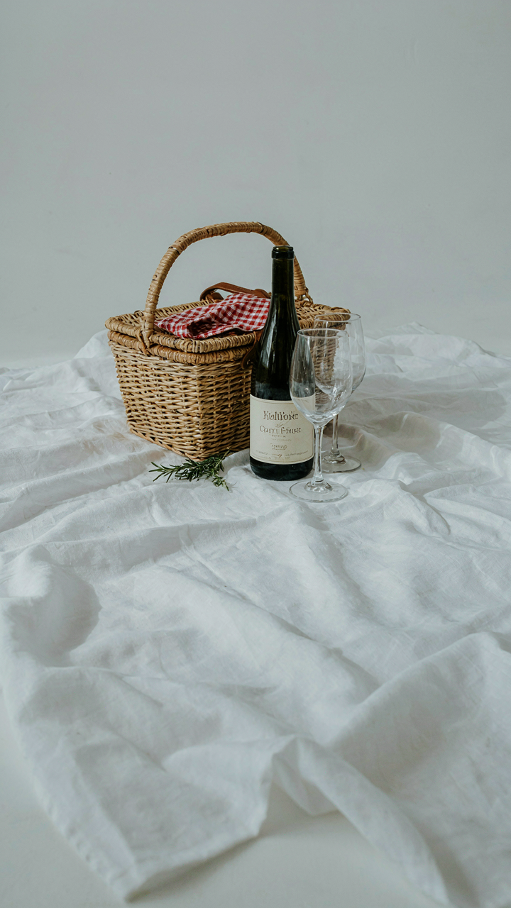 A perfectly arranged minimalist picnic basket sits on a white blanket at sunset.