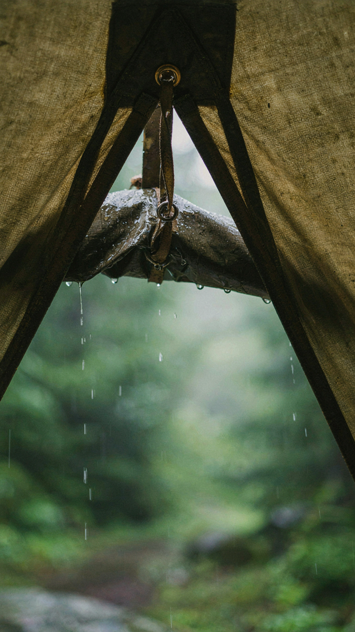 A tent's vent is open, showing moisture inside the tent and rain outside.