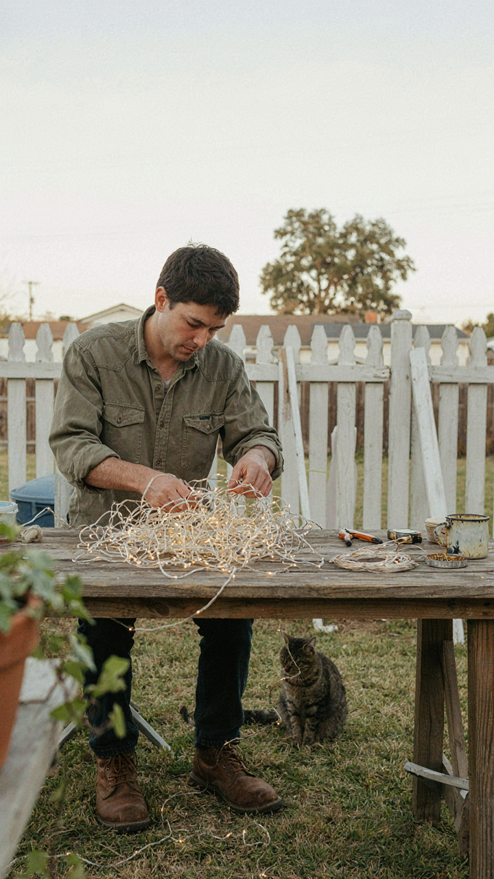 A person struggles to untangle a large knot of fairy lights.