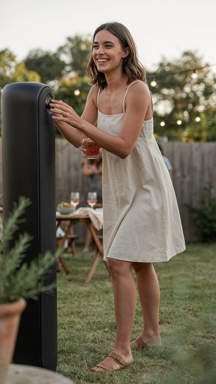 A person confidently turns up the volume on an outdoor speaker setup.
