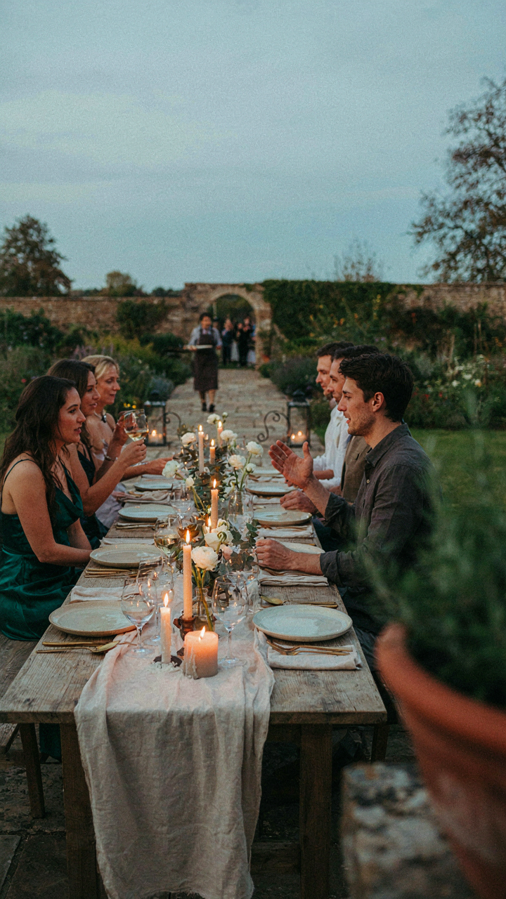 An outdoor dinner party with subtle, artfully placed lighting highlighting specific areas.
