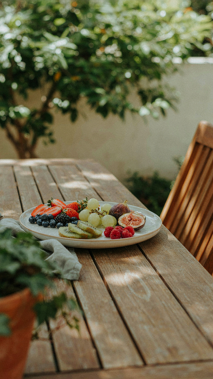 A simple, fresh garden party fruit platter sits on a shaded patio table.