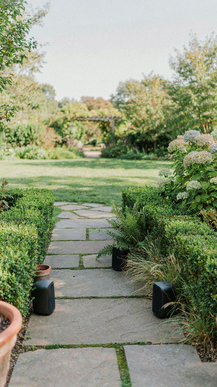 Multiple small, discreet speakers are placed strategically around a garden path.