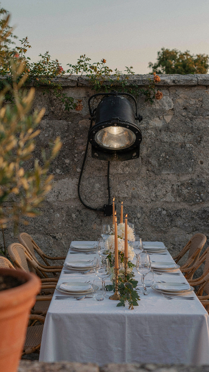 A clunky industrial floodlight fixture stands out in an elegant outdoor dinner setting.