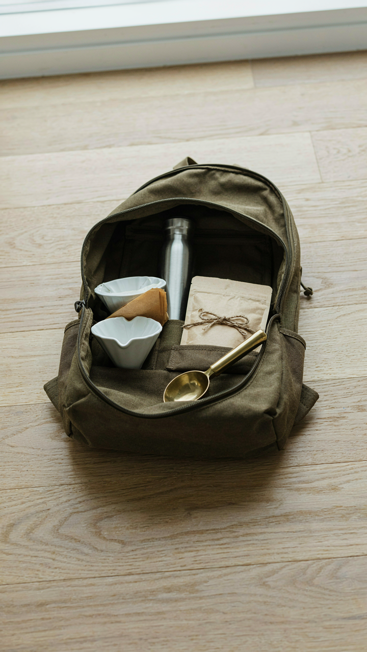 A compact backpack is open, showing neatly packed camping coffee gear.