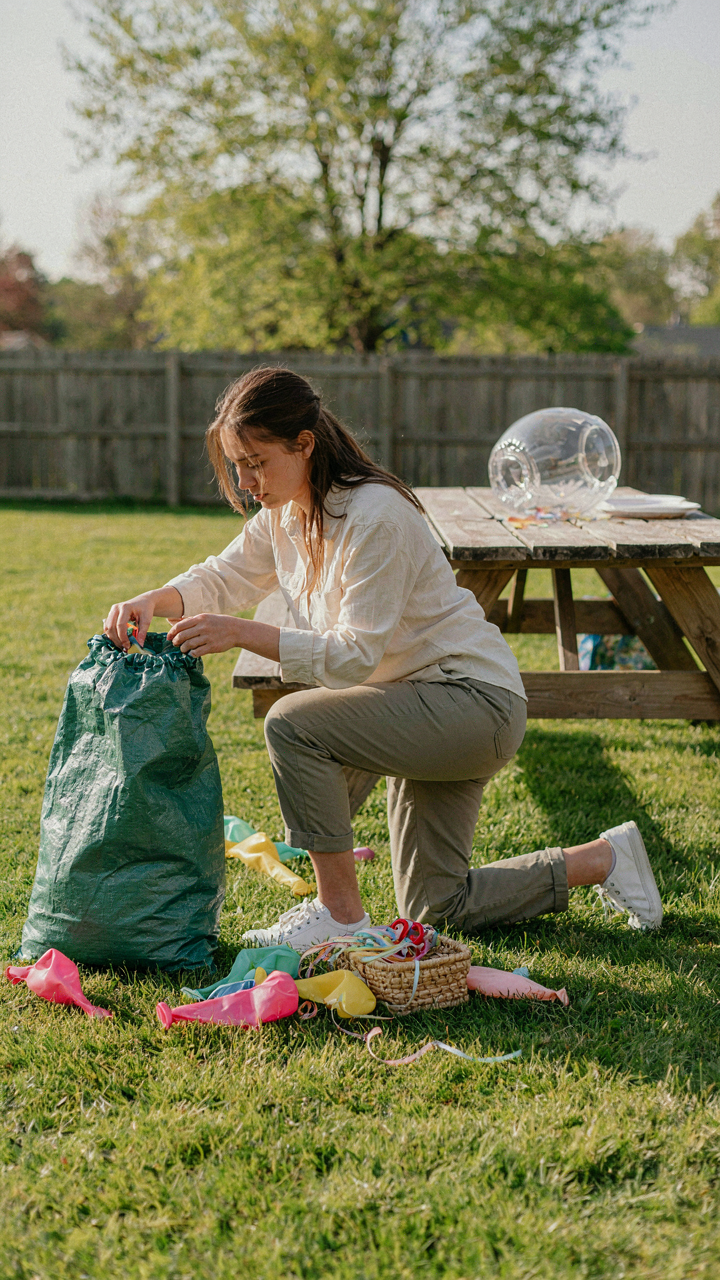 A person quickly gathers deflated balloons into a recycling bag after a party.