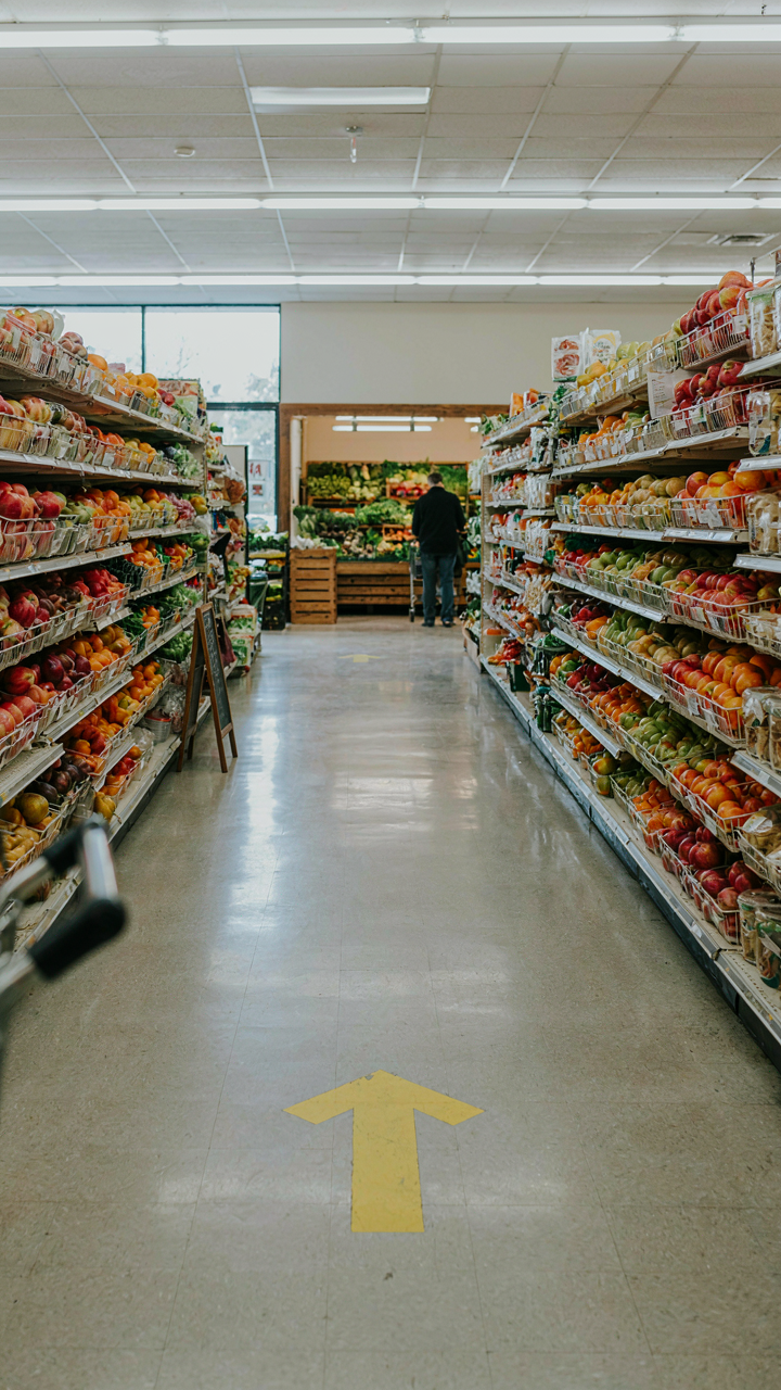 A subtle arrow sticker on a grocery store floor points to produce.