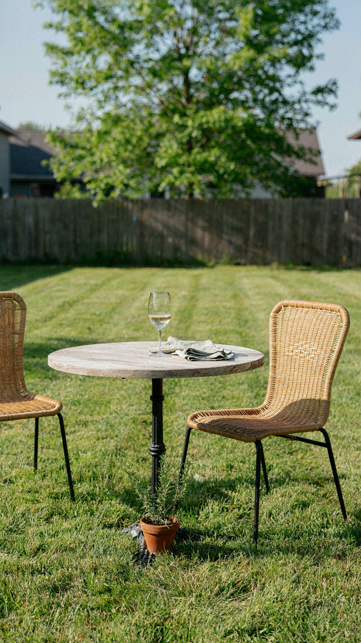 A simple backyard bistro set up with a table and two chairs on grass.