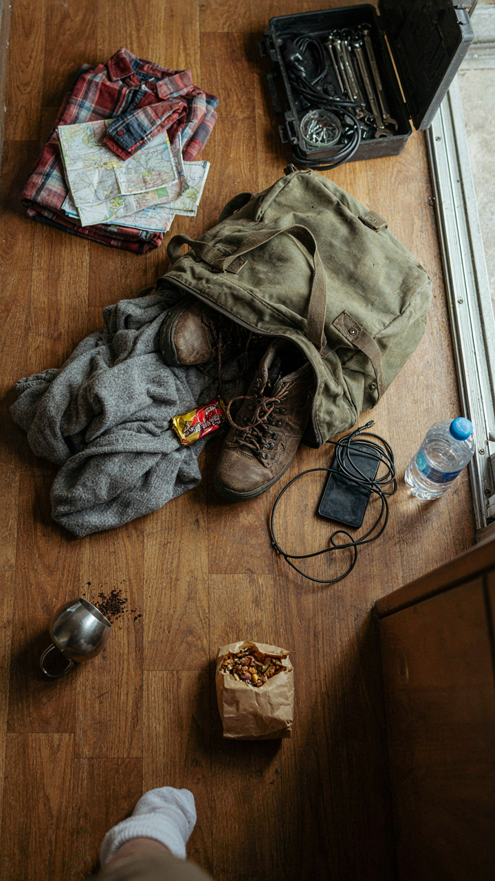 A camper trailer floor covered with piles of items, some trash.