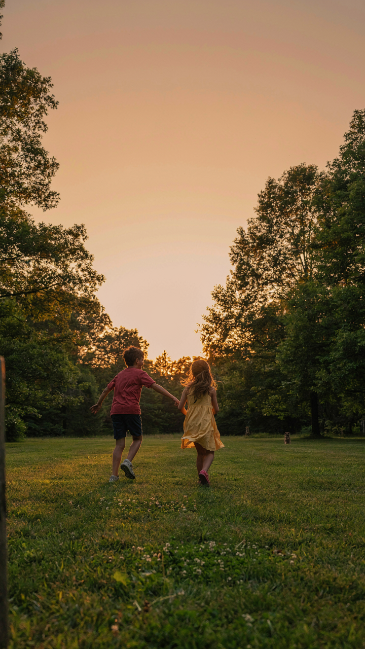 Children playing tag in a grassy backyard at sunset.