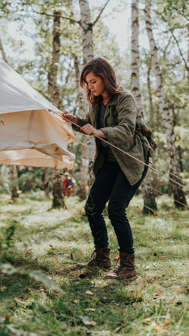 A person adjusts a bell tent line in windy weather.