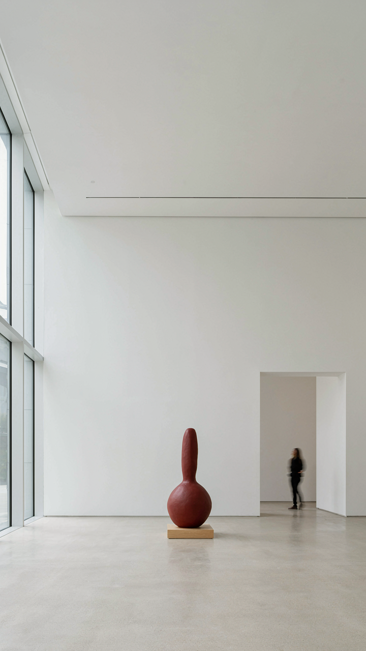 A spacious, minimalist art gallery with one sculpture in the middle.