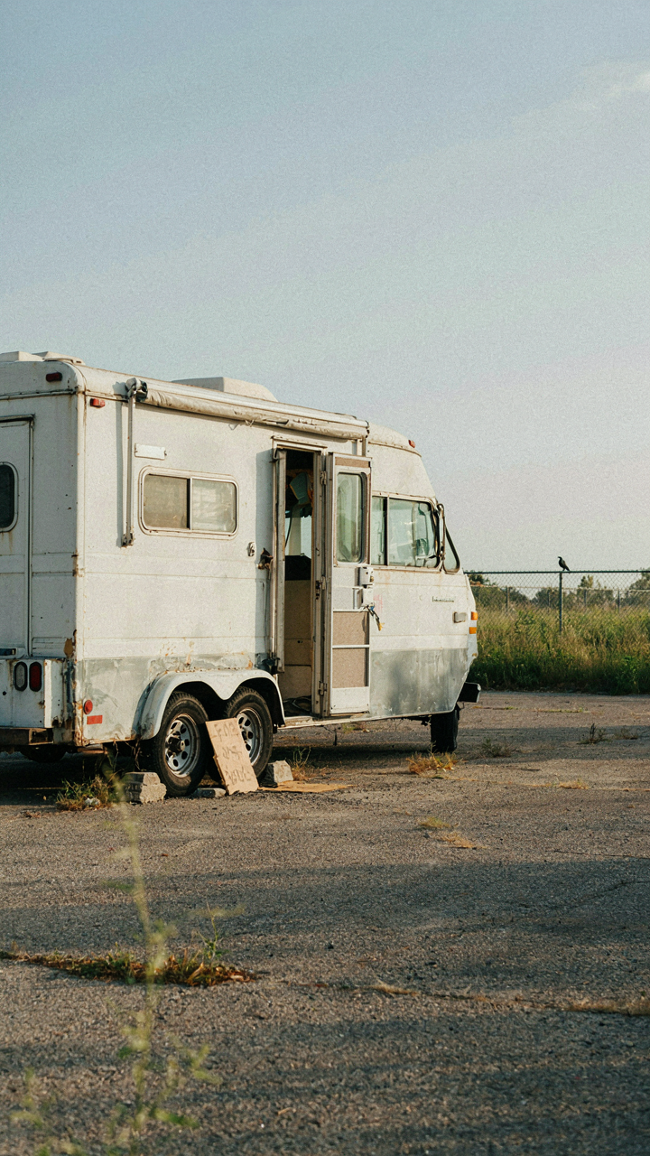 A used cargo trailer camper conversion for sale in an empty lot.