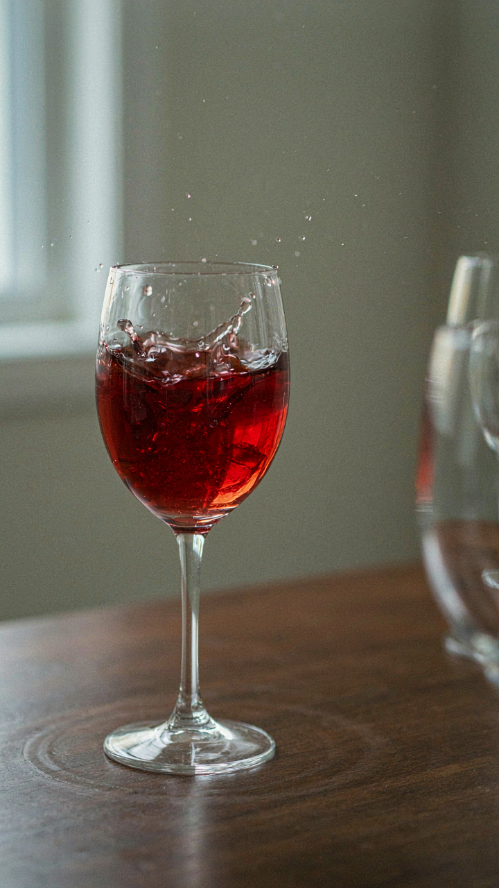 A wine glass vibrates strongly on a table, making ripples in the liquid.