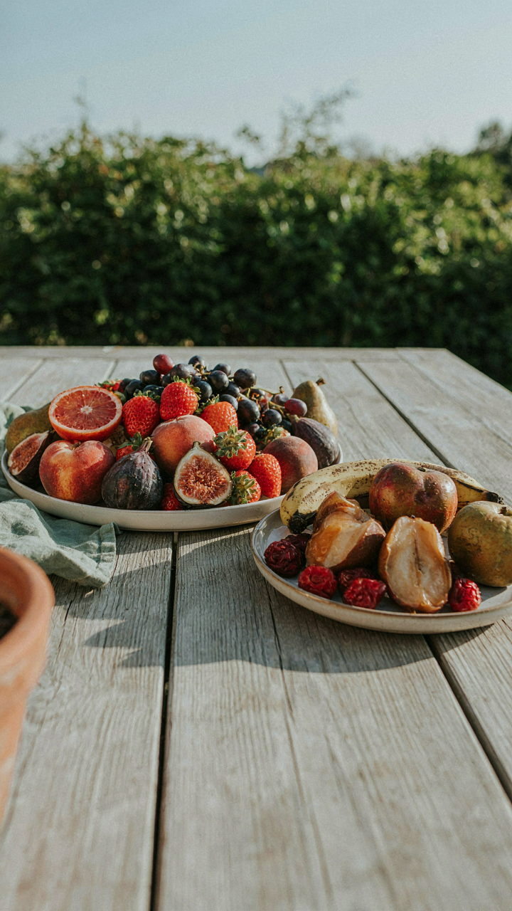 A fresh, ripe garden party fruit platter sits next to a browning fruit platter.