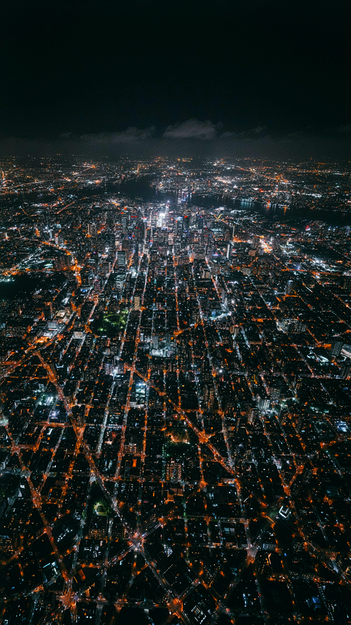 An aerial view of a city at night shows a network of lights.
