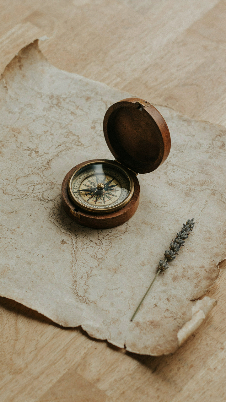 A lone antique wooden compass sits on an old map.