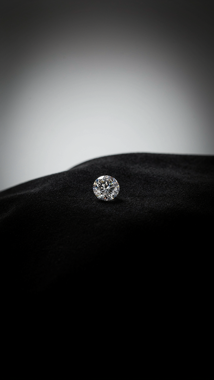 A sparkling diamond rests alone on a black velvet cloth.