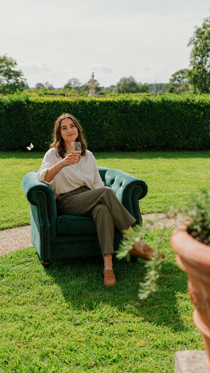 One person sits comfortably in a luxurious armchair in a garden.