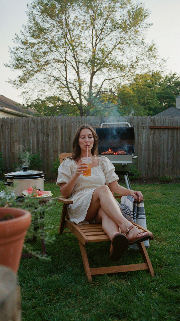 A person relaxes in a chair while food cooks nearby.