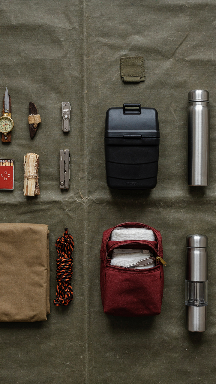 A survival kit with compact tools and a portable toilet on a canvas.
