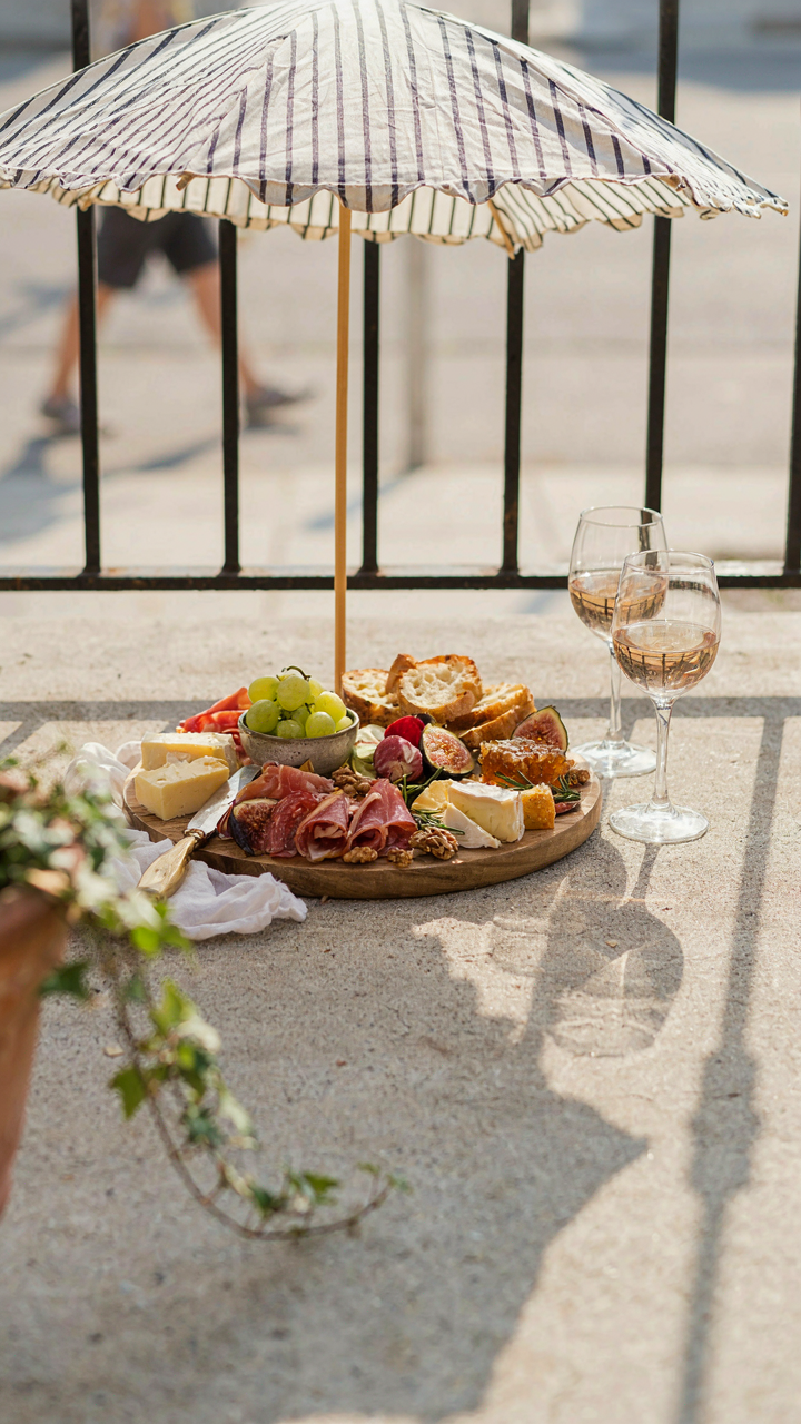 A charcuterie board under an umbrella, with bright reflections from nearby surfaces.