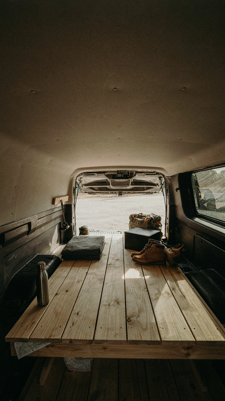 A minimalist truck bed camper interior with only a bed and a small storage box.