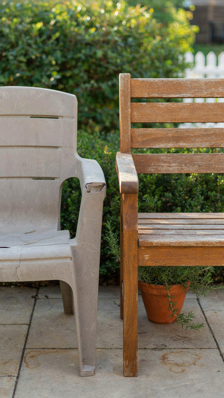 A broken plastic chair next to a durable teak chair.