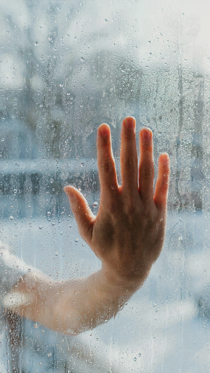 A warm hand presses against a cold glass window, showing heat transfer.