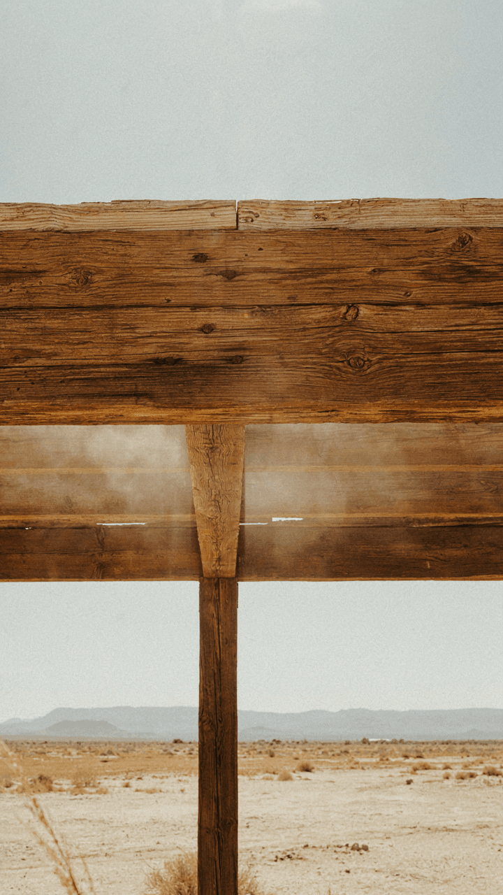 Heat waves radiate from a thick timber beam in a desert pergola.
