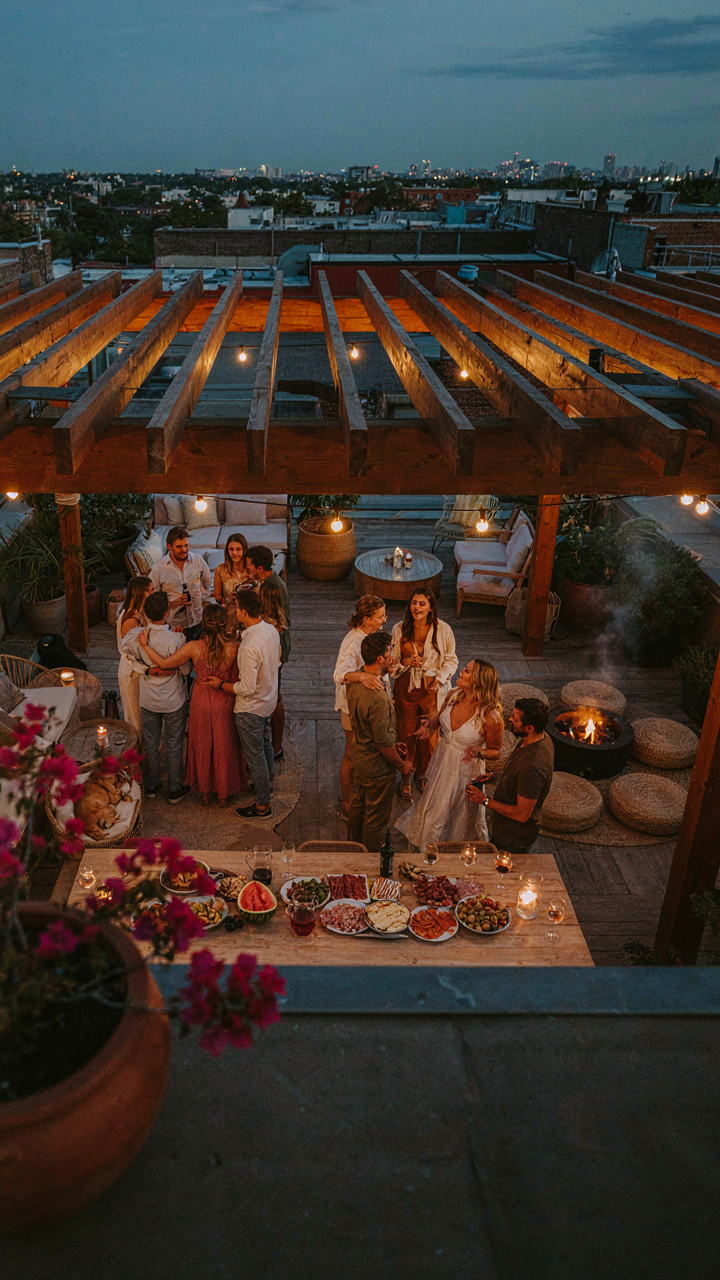 An aerial view of an evening party under string lights over a pergola.