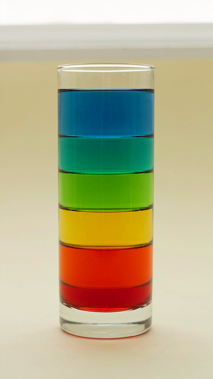 Different liquids are perfectly layered in a glass, showing density changes.