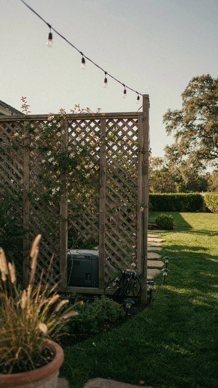 A quiet portable generator hidden behind a screen in a backyard.